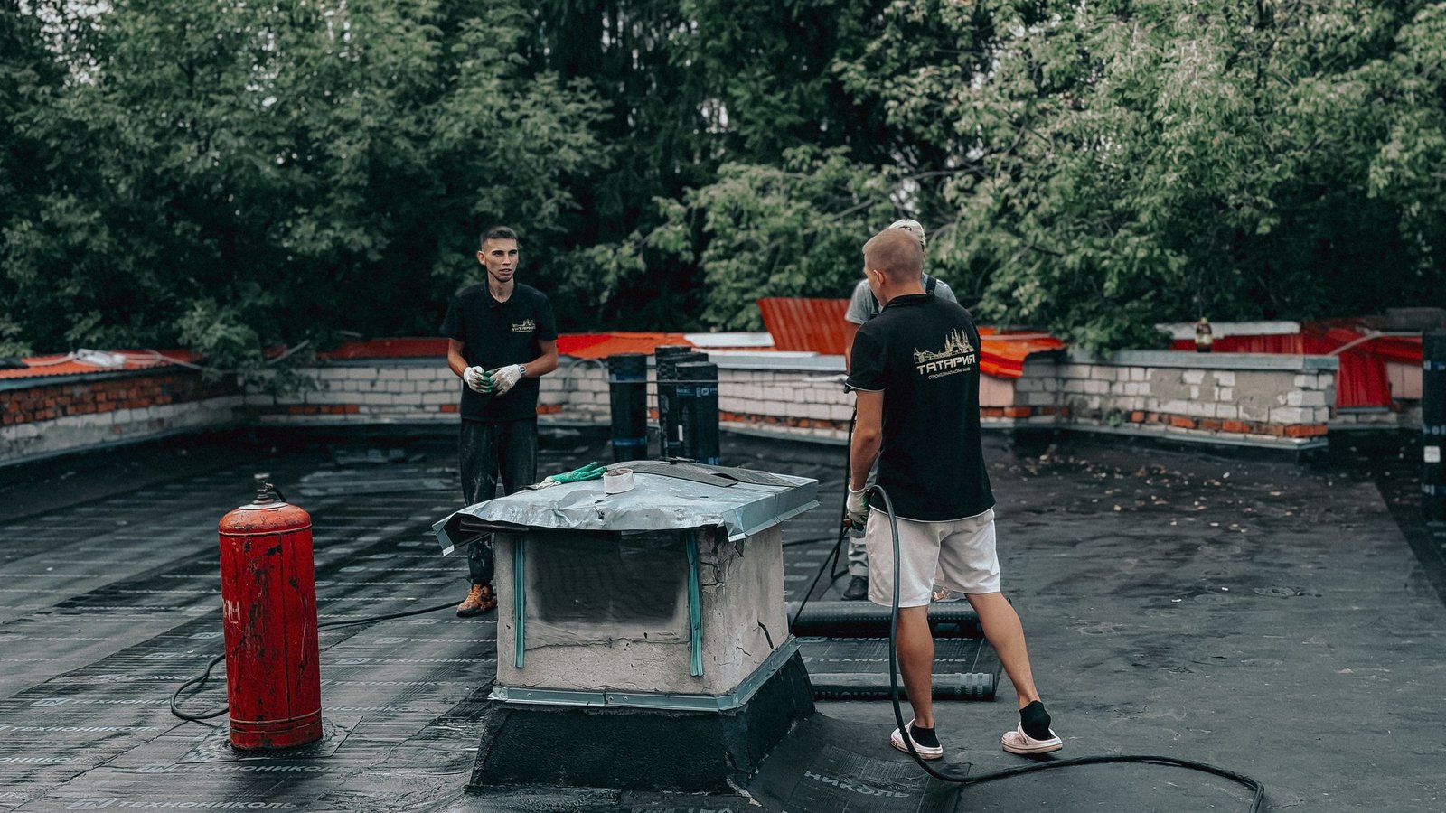 Roofing crew working on a flat roof membrane - Homex Builders